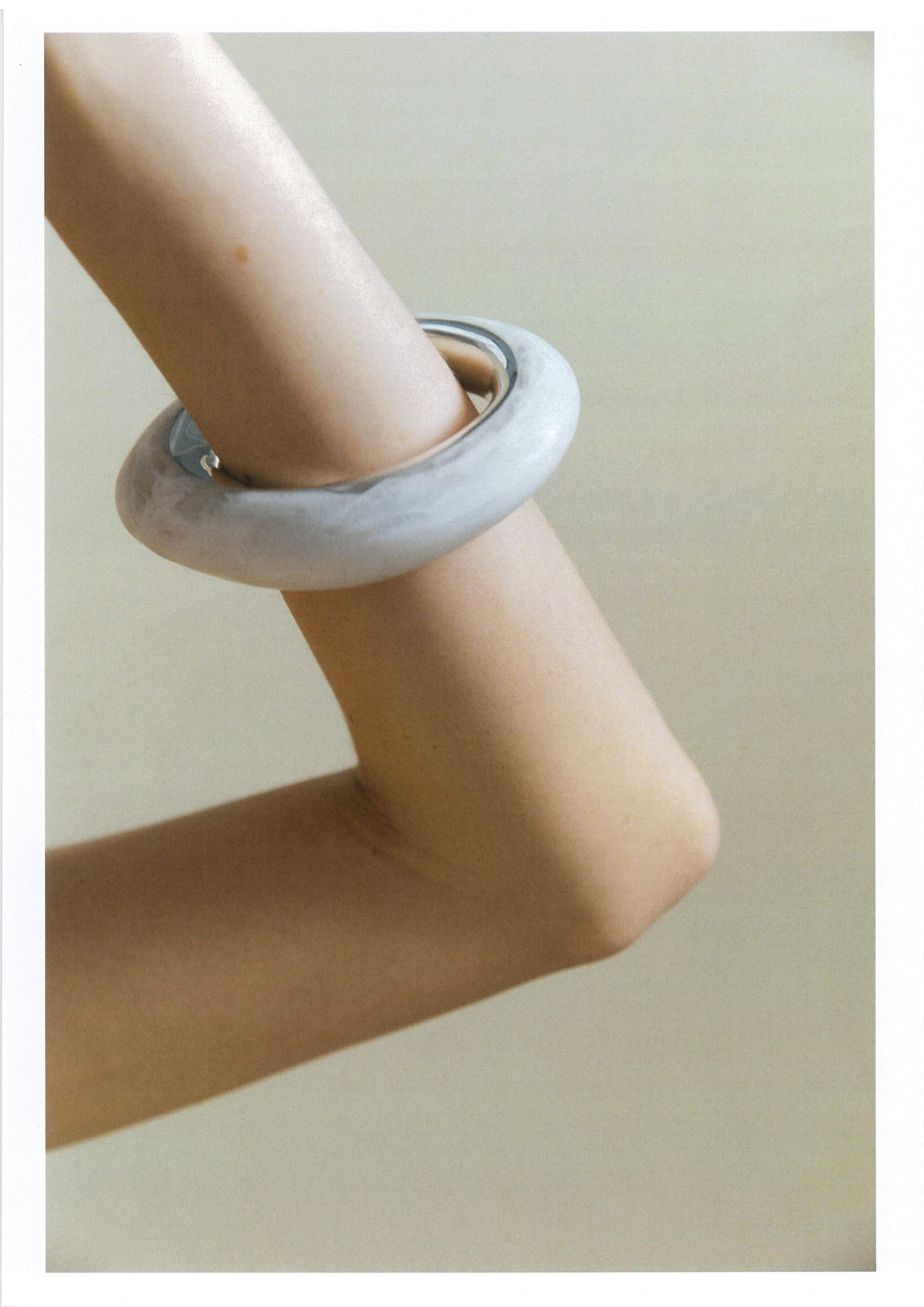 Marble-patterned bracelet on a person's wrist against a neutral background