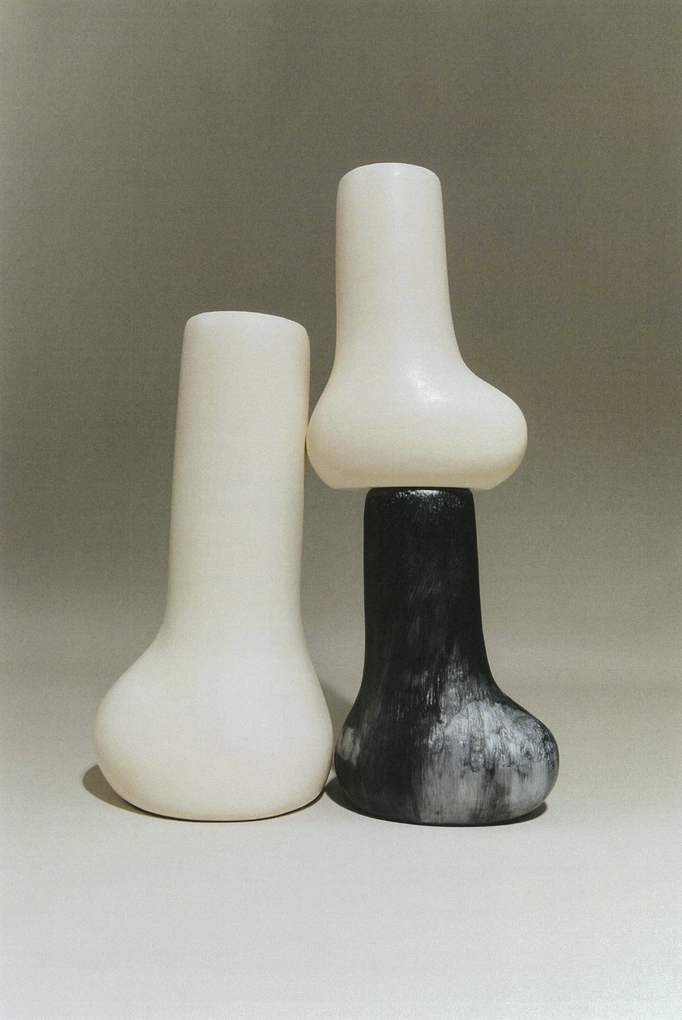 Two unique vases, one white and one black and white patterned, on a neutral background.