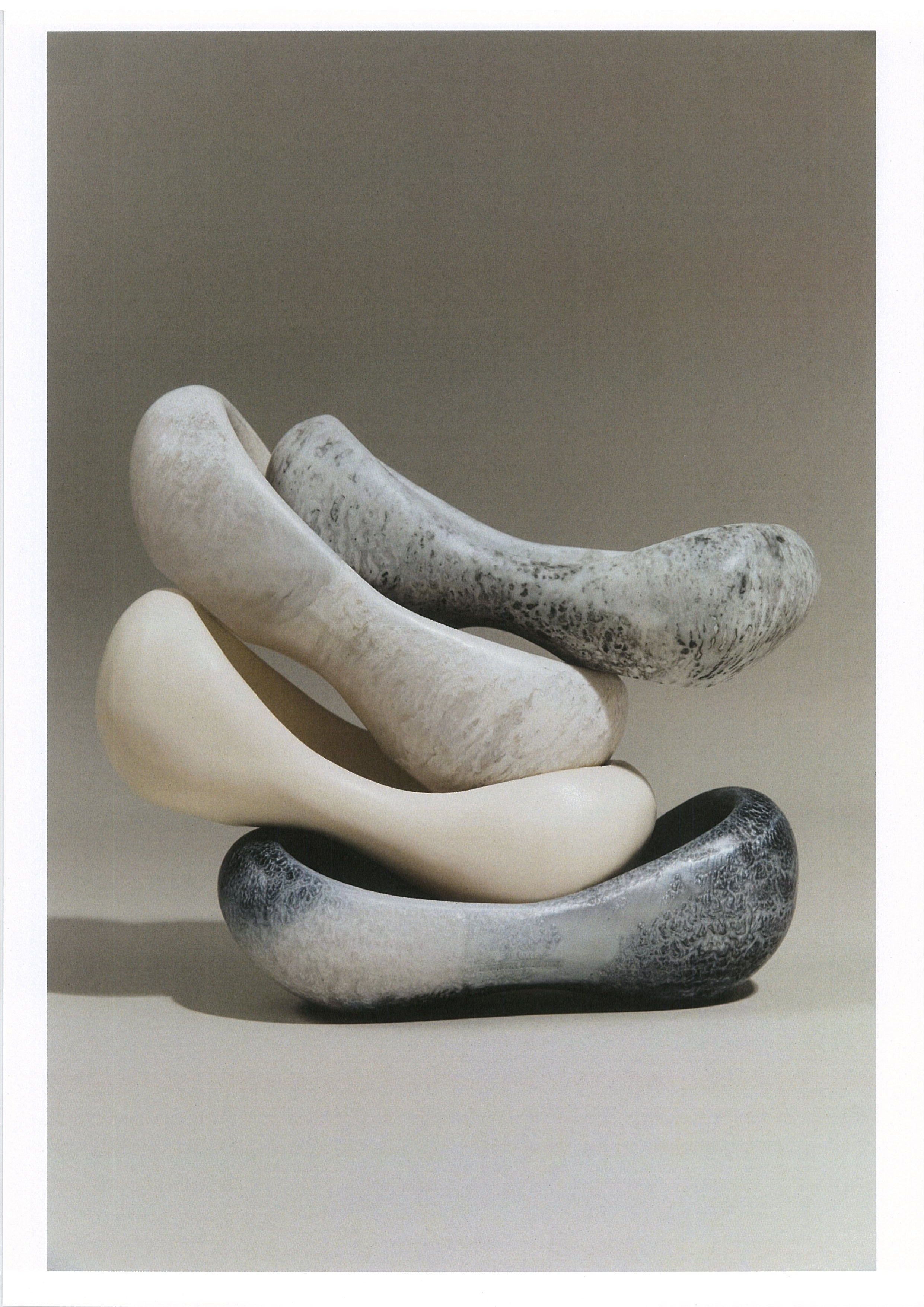 Stack of resin side bowls in various shapes and grey tones on a neutral background