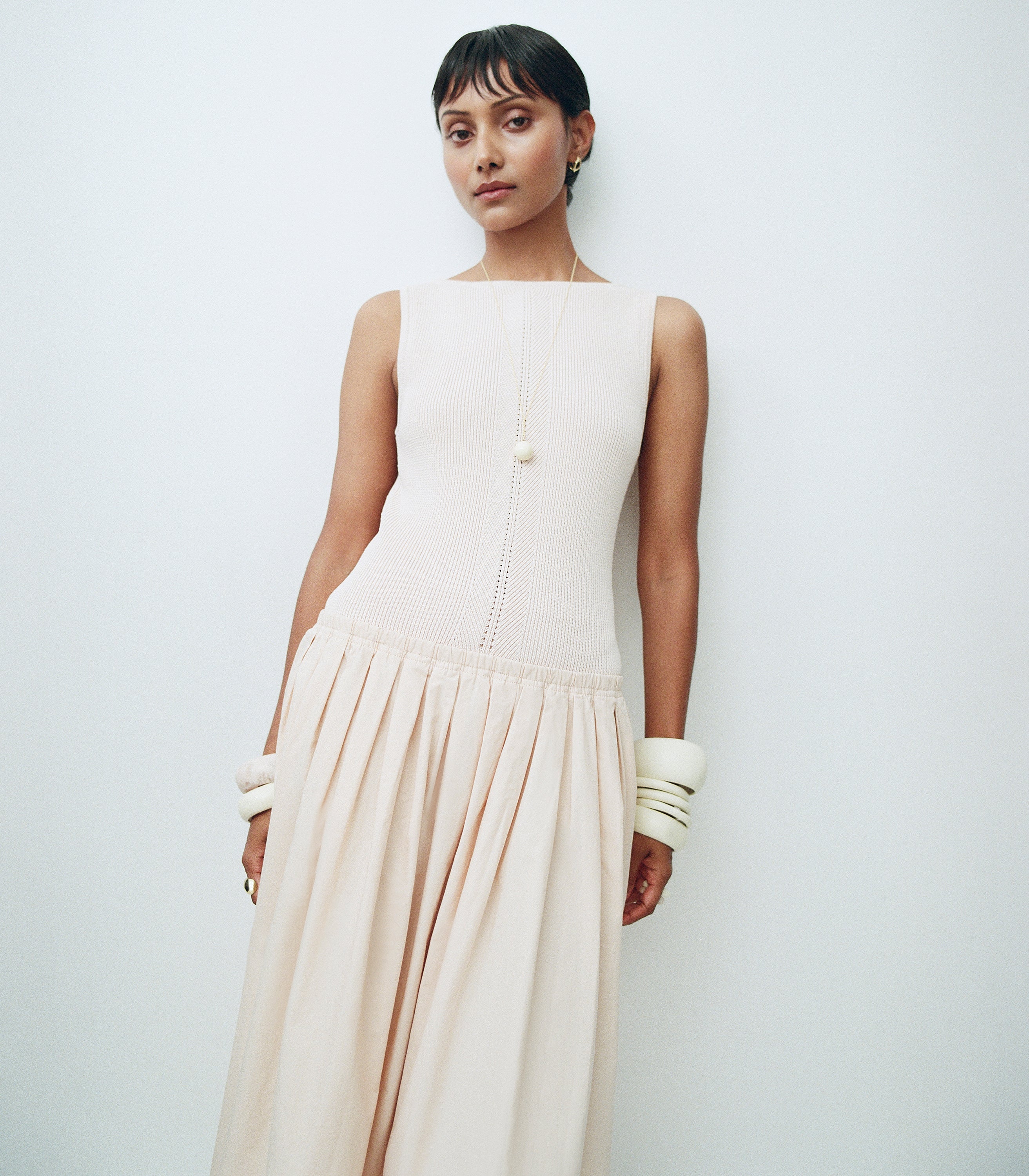 Model wearing knit beige dress with cream resin bangles