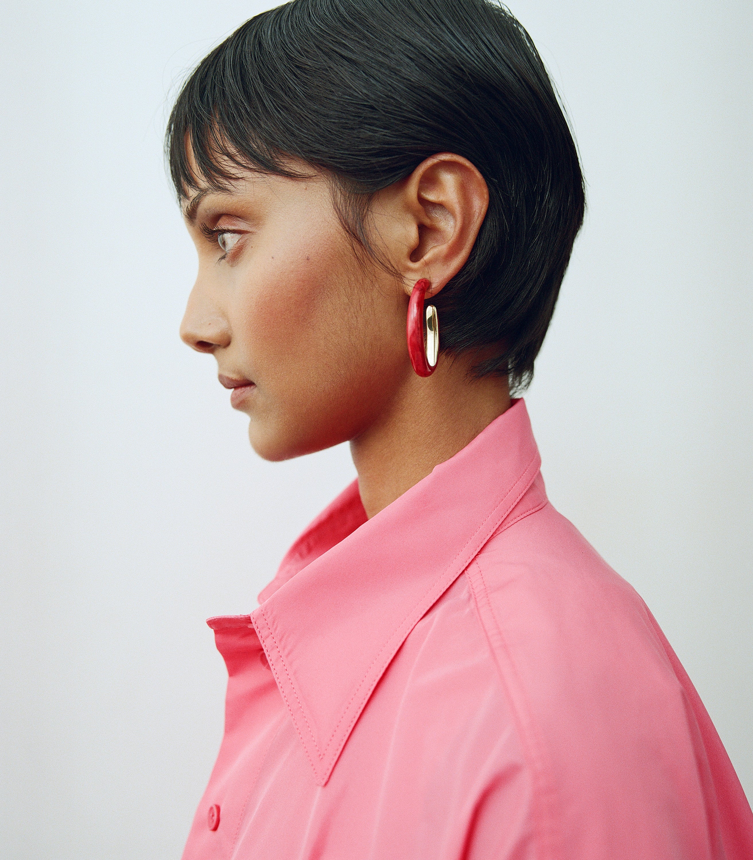 Model wearing pink shirt with deep pink hoop earrings with brass accents