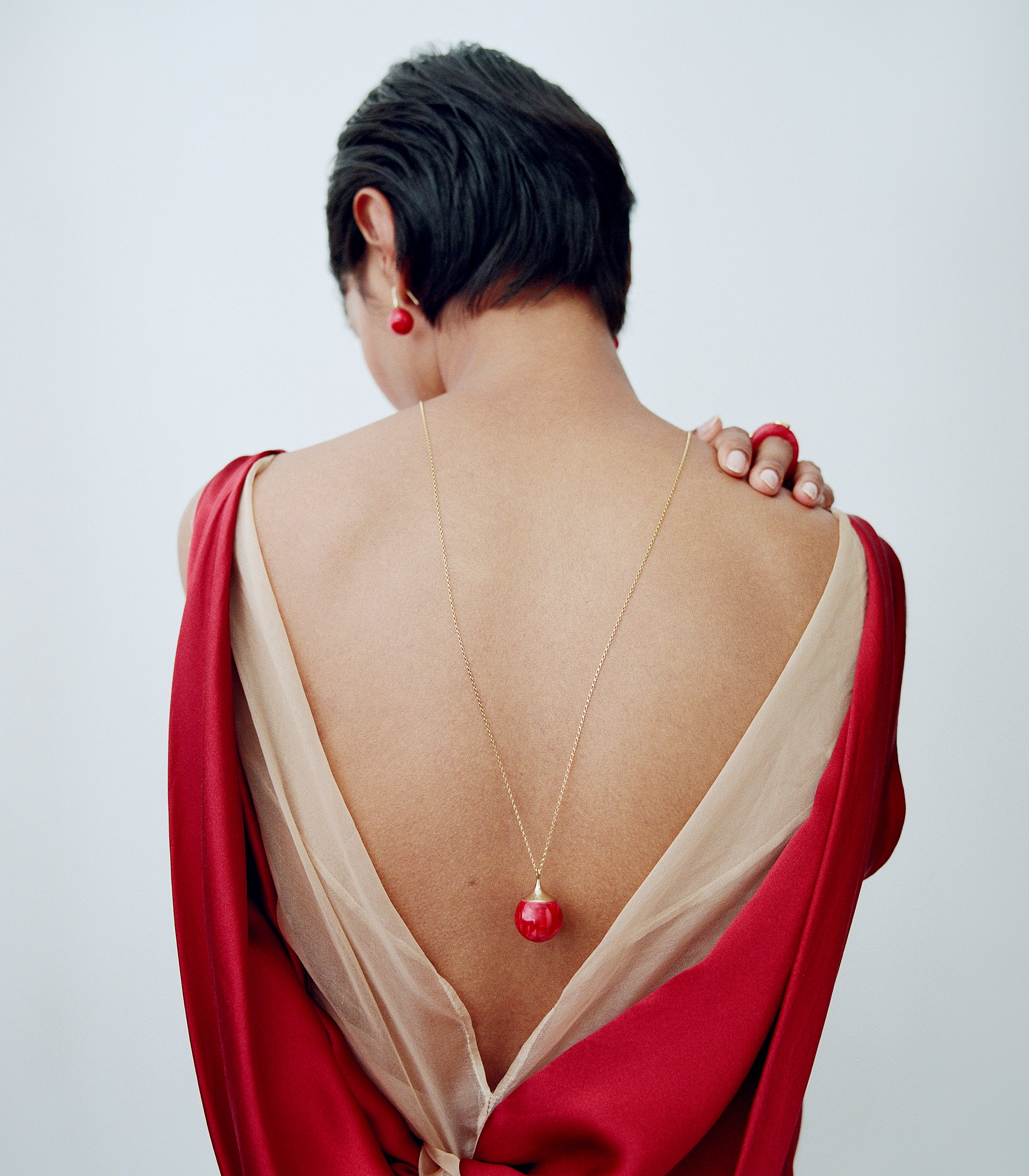 Model wearing pink toned pendant with brass accents