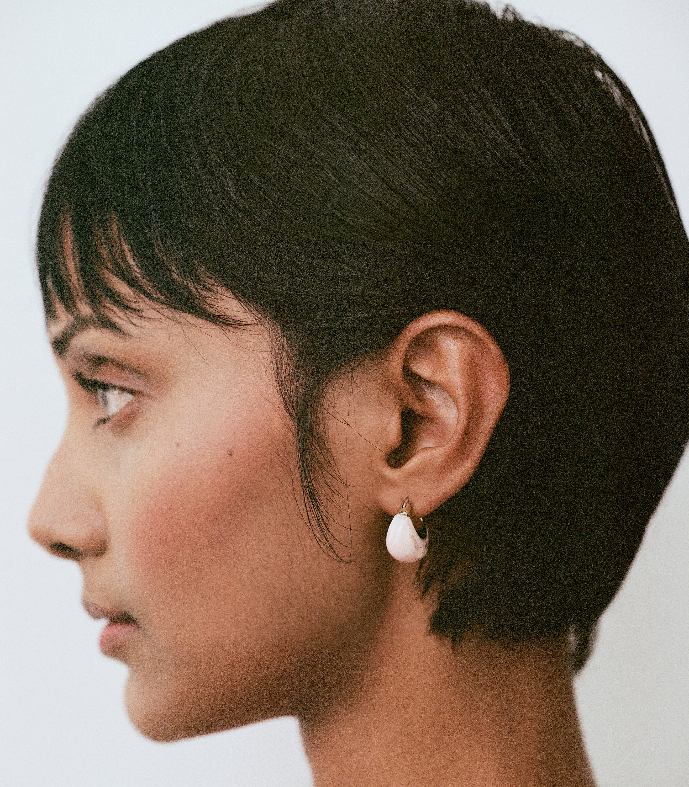 Model wearing pink and brass small hoop earrings
