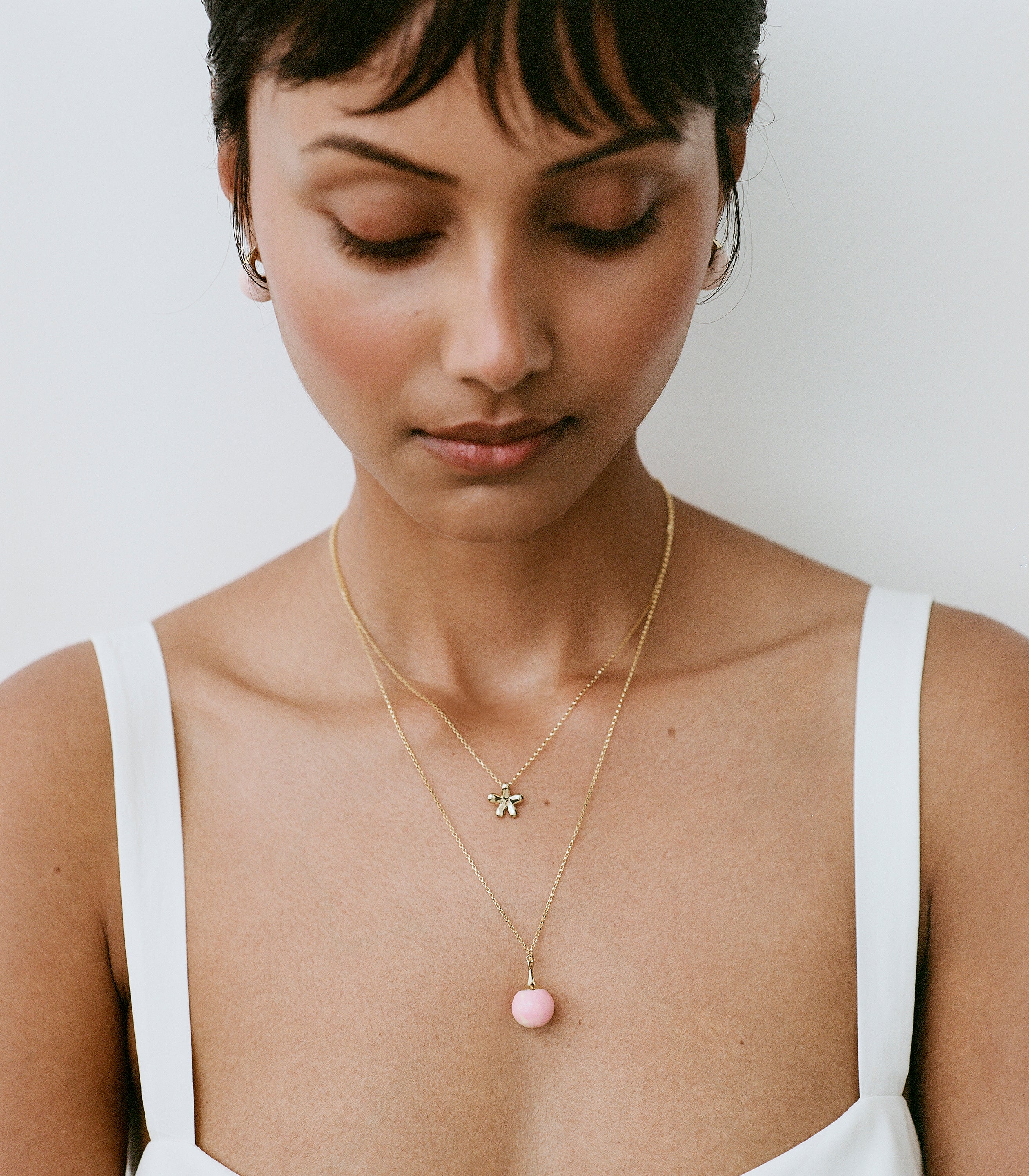 Model wearing brass pendant with pink ball pendant accent