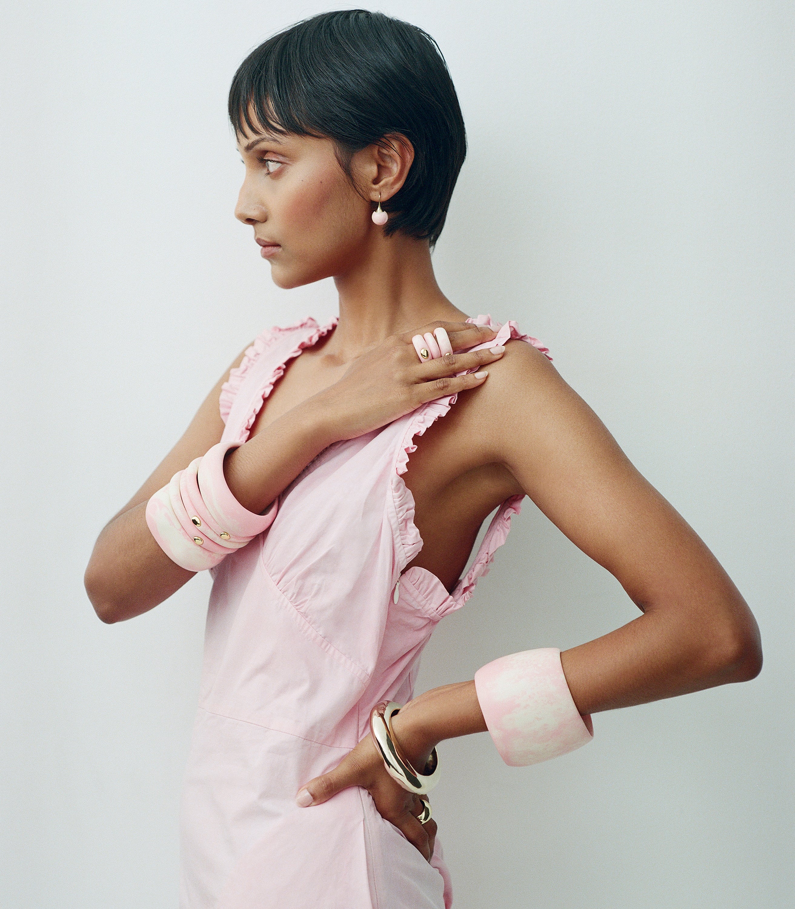 Model wearing pink dress with pink toned resin bangles and rings with brass accents