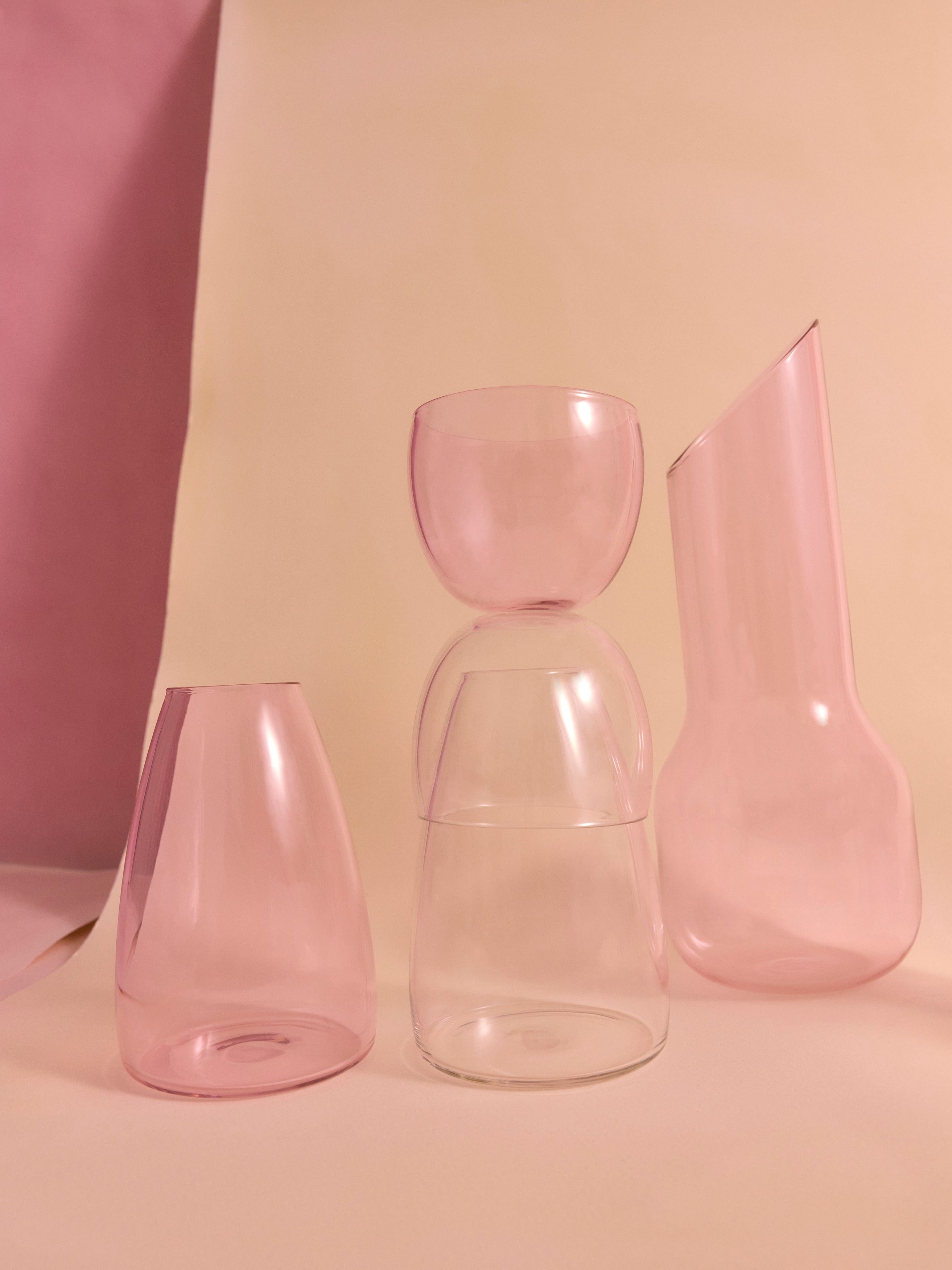 Pink decanter with pink and clear glass carafe on a beige and pink backdrop