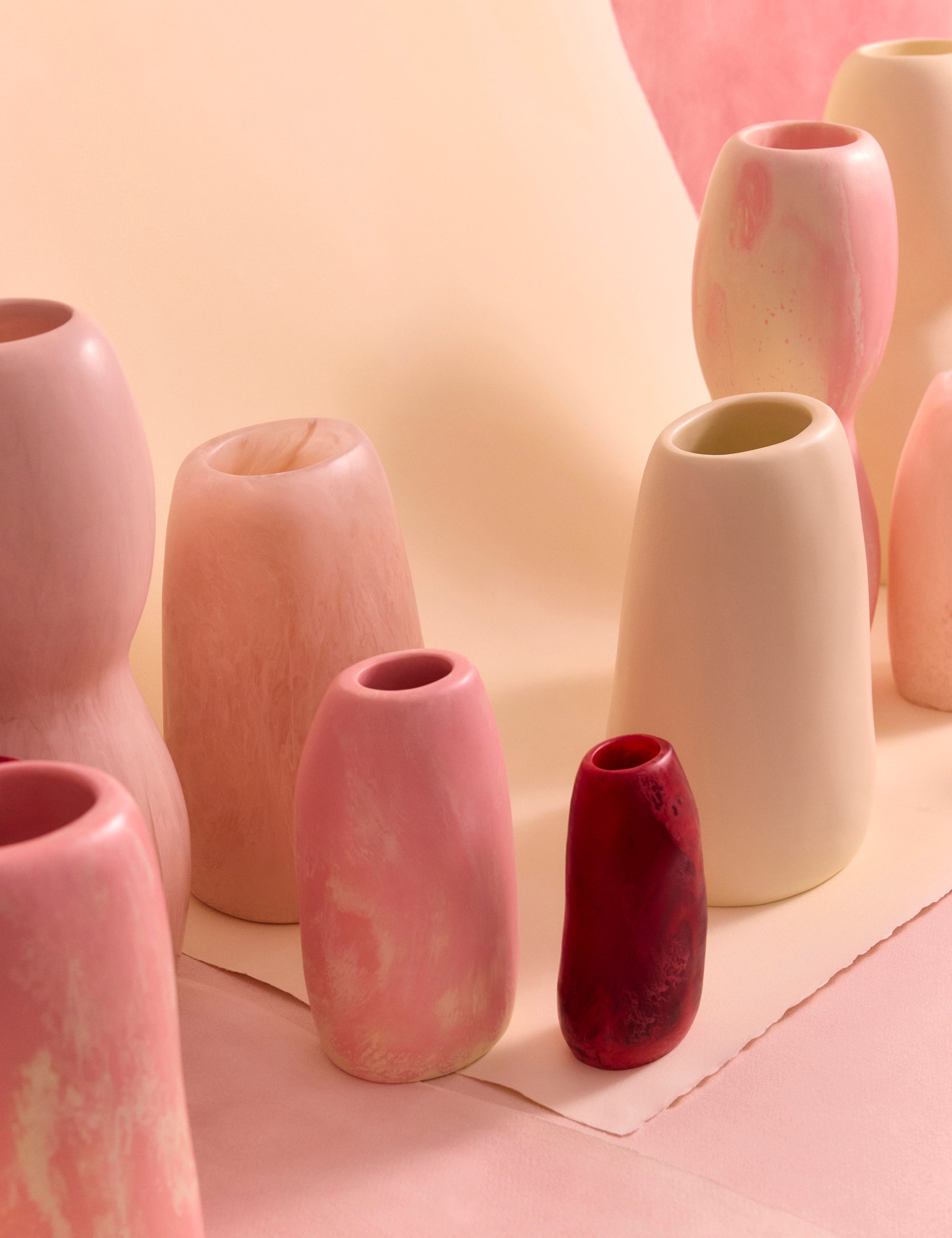Collection of resin vases in various pastel pinks and creams on a soft pink background