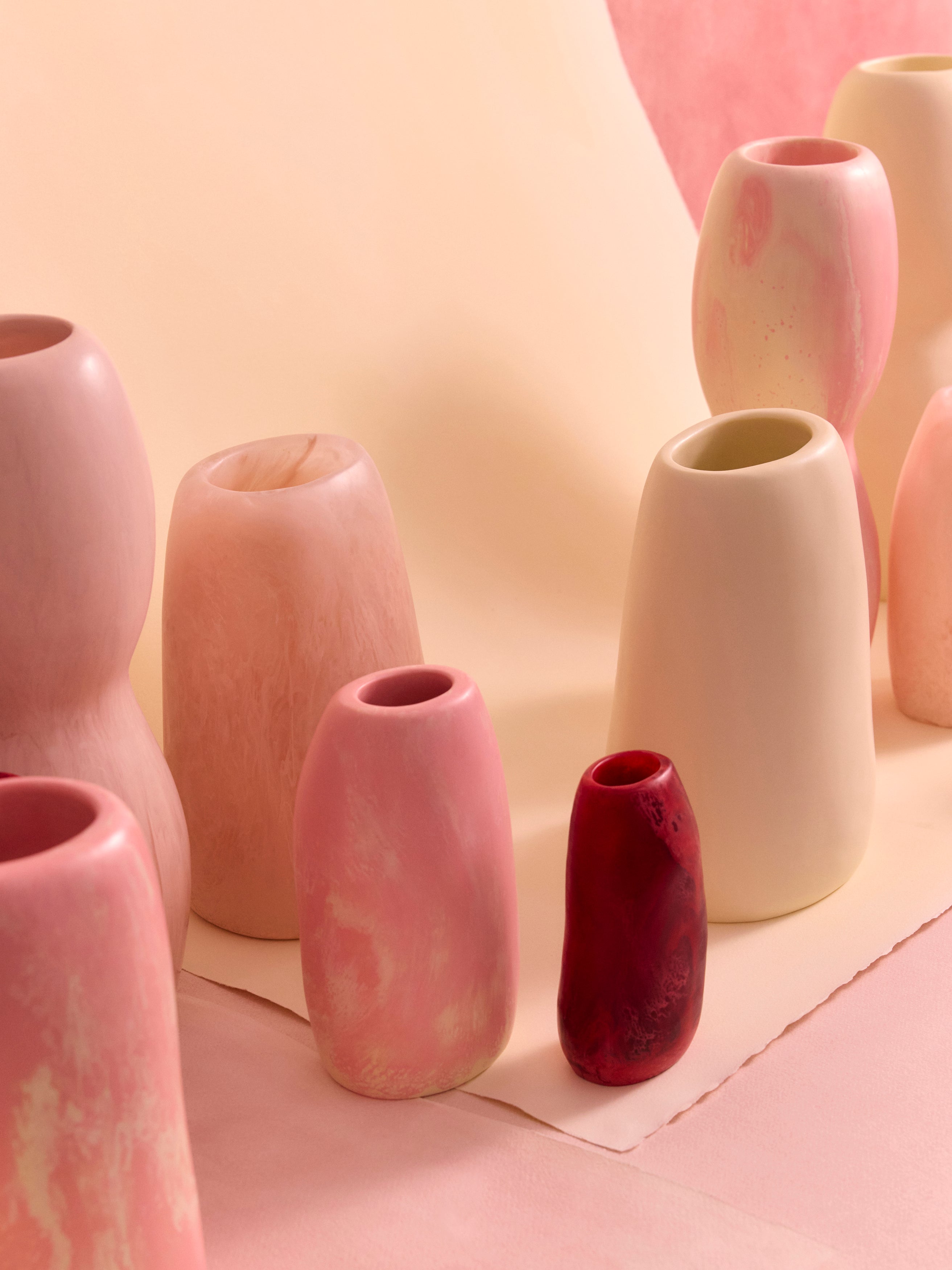 Collection of resin vases in various pastel pinks and creams on a soft pink background