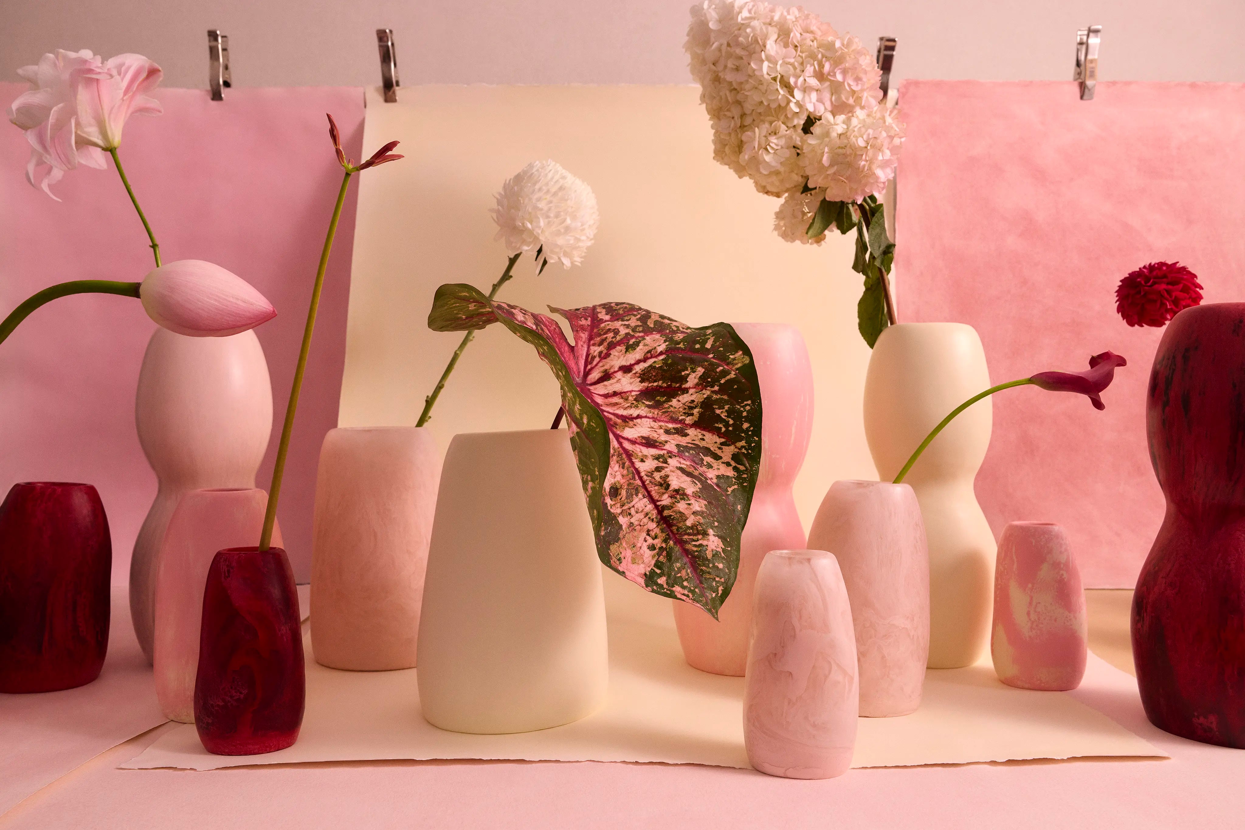 A collection of pink and cream resin vases with a variety of different floral stems