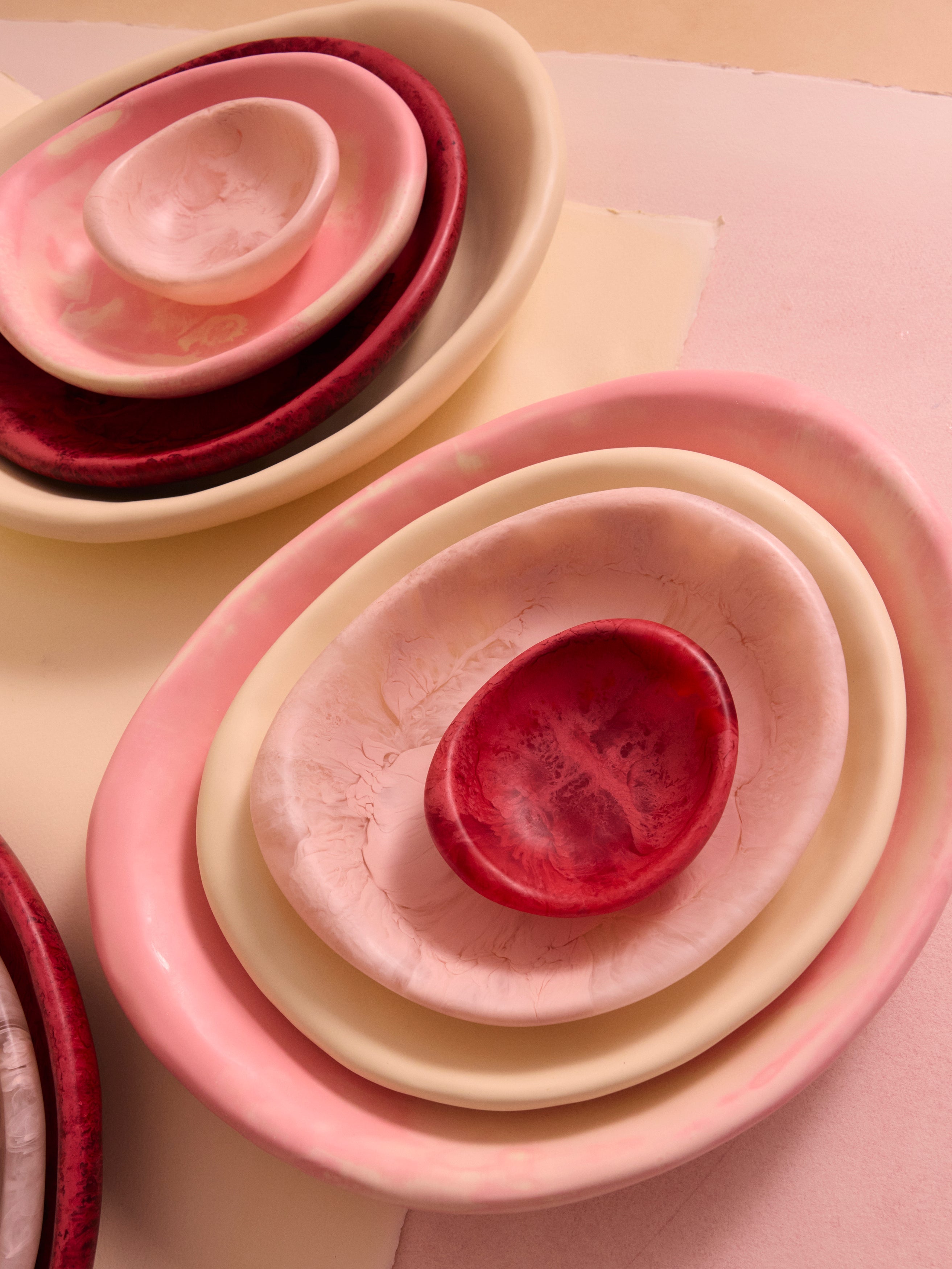 Set of nested resin bowls in pink and cream on a light background