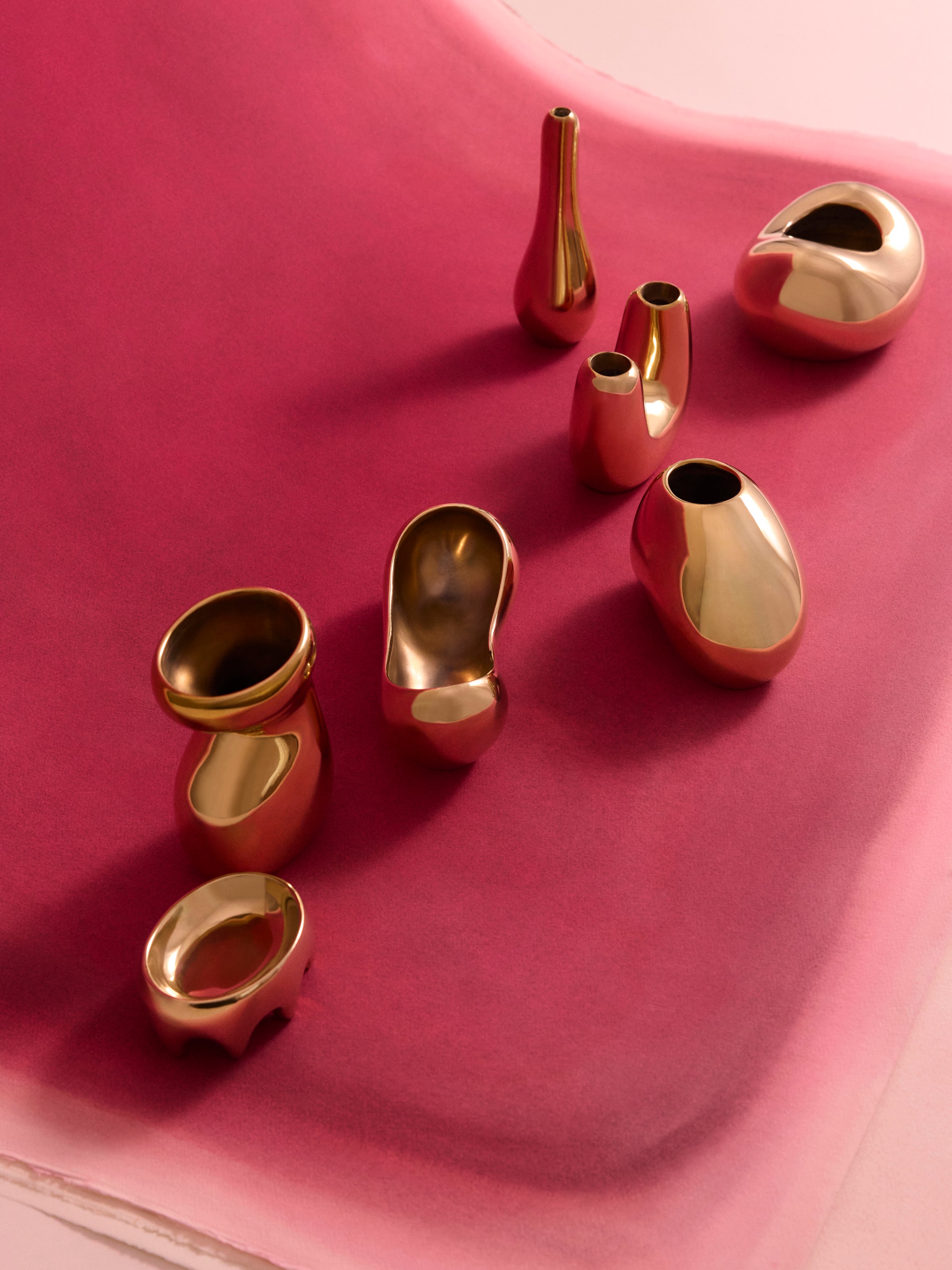 Variety of sculptural brass vases on a pink backdrop