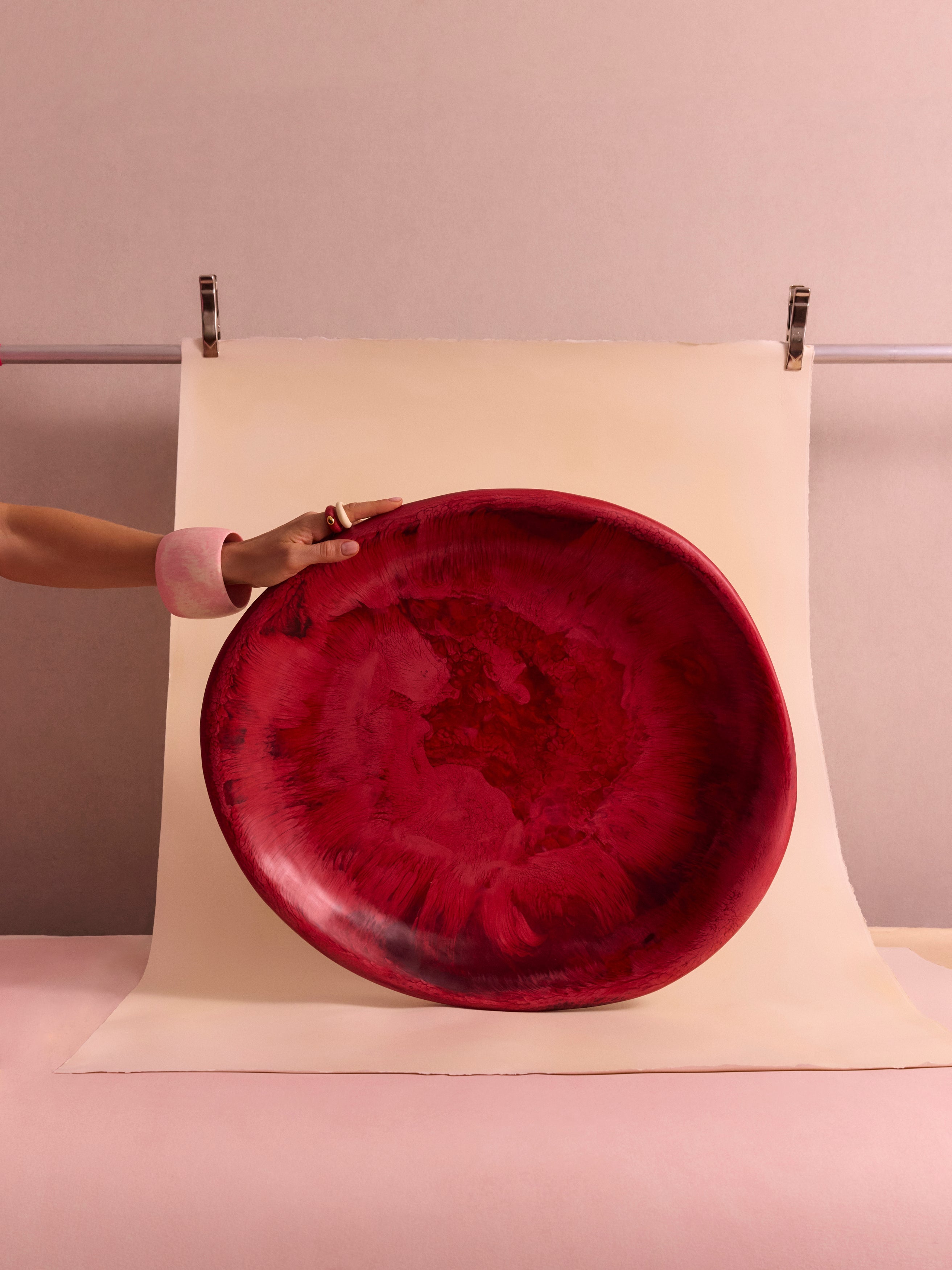 Large deep pink serving bowl held up o a beige and pink backdrop