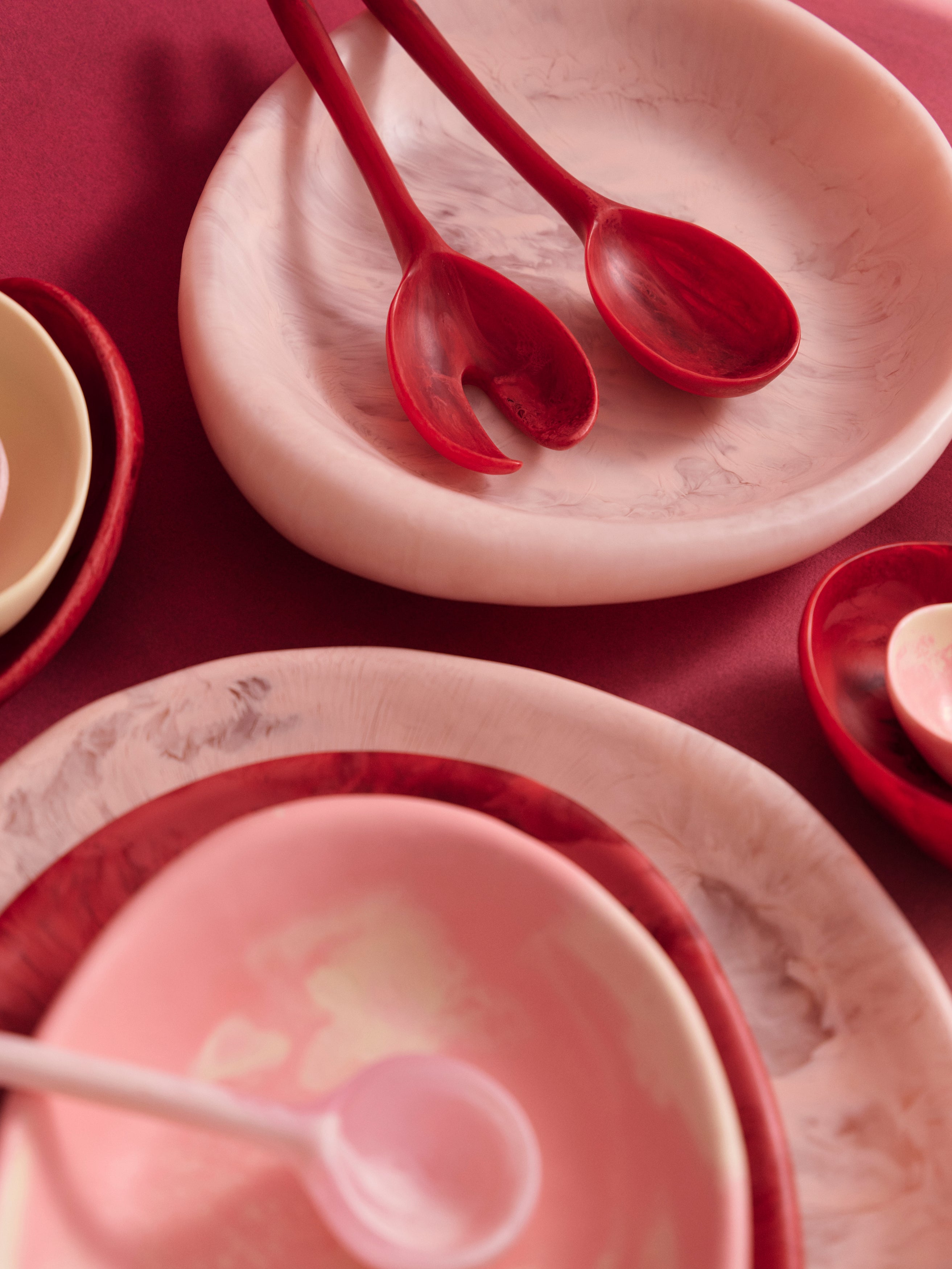 Various serving bowls accompanied by serving spoons in pink tones