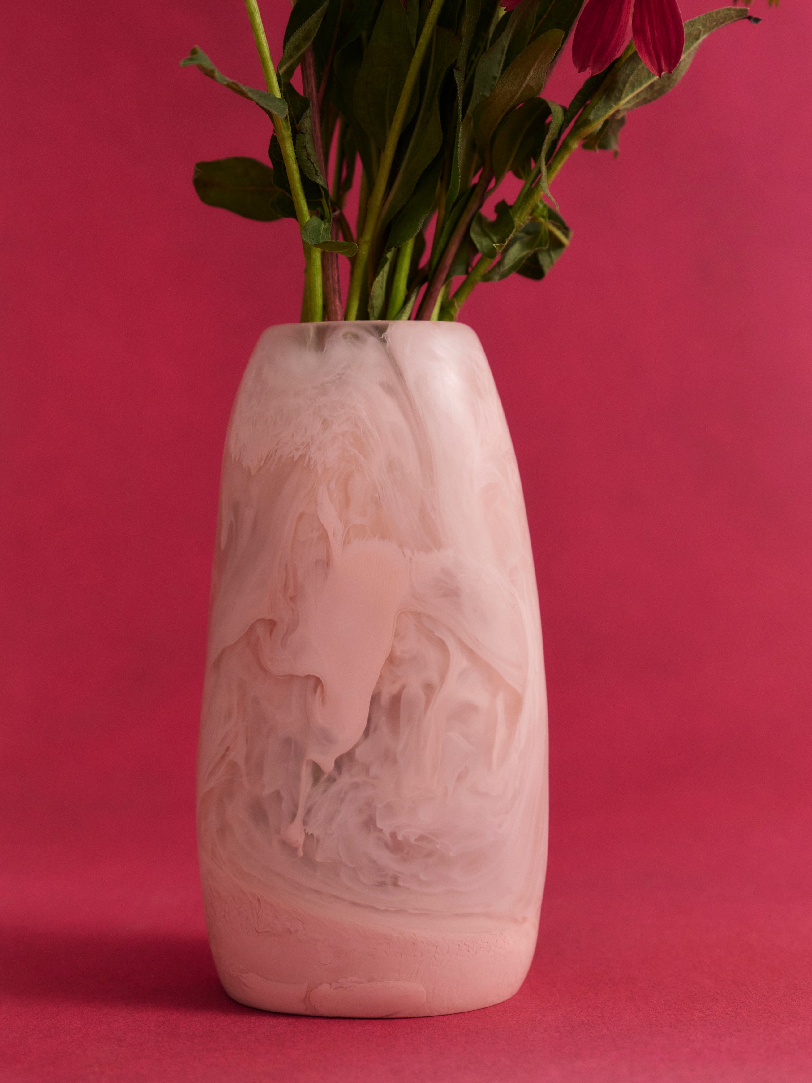Decorative pink resin vase with floral arrangement on a pink background