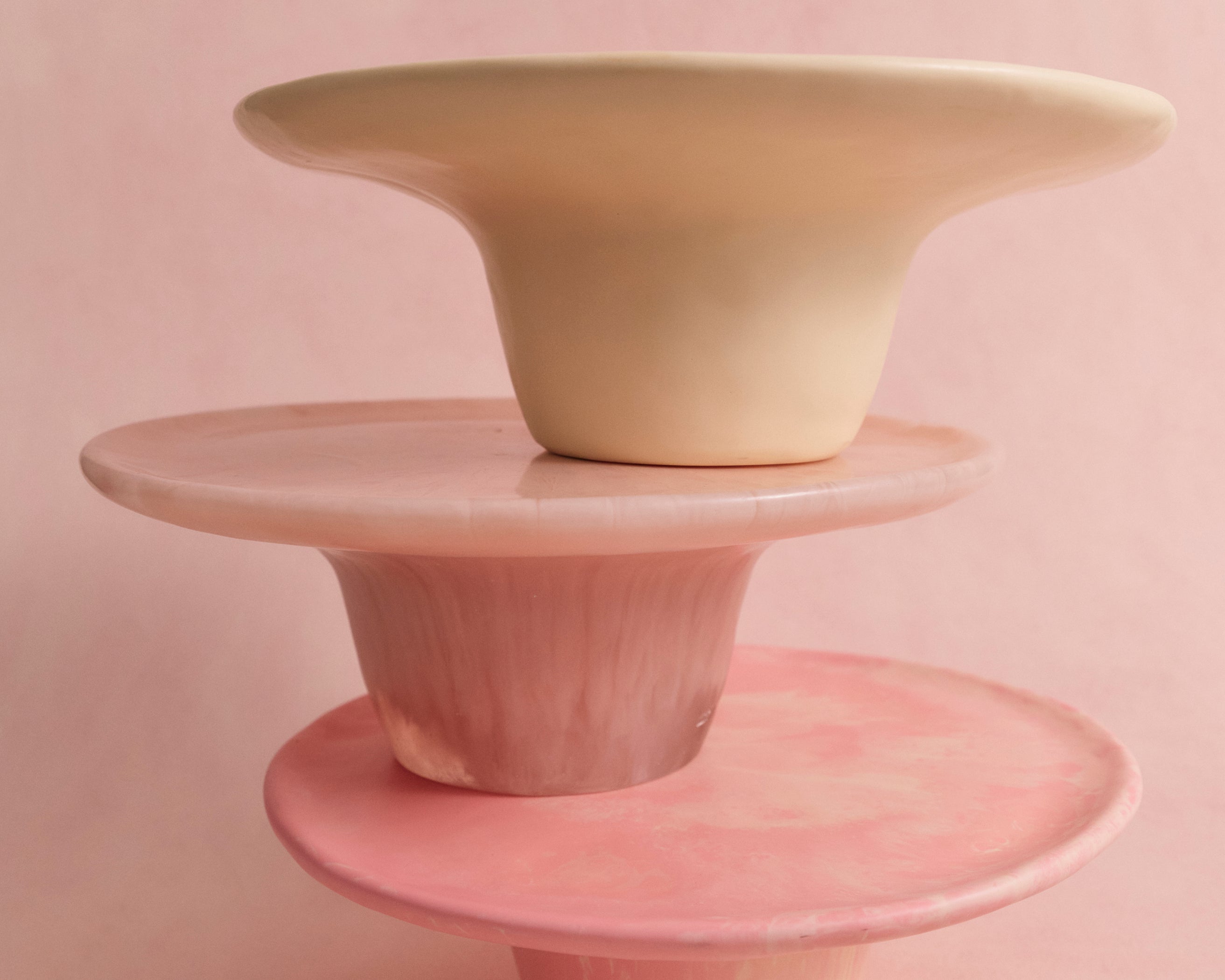 Three resin cake stands in pinks and cream stacked upon one another