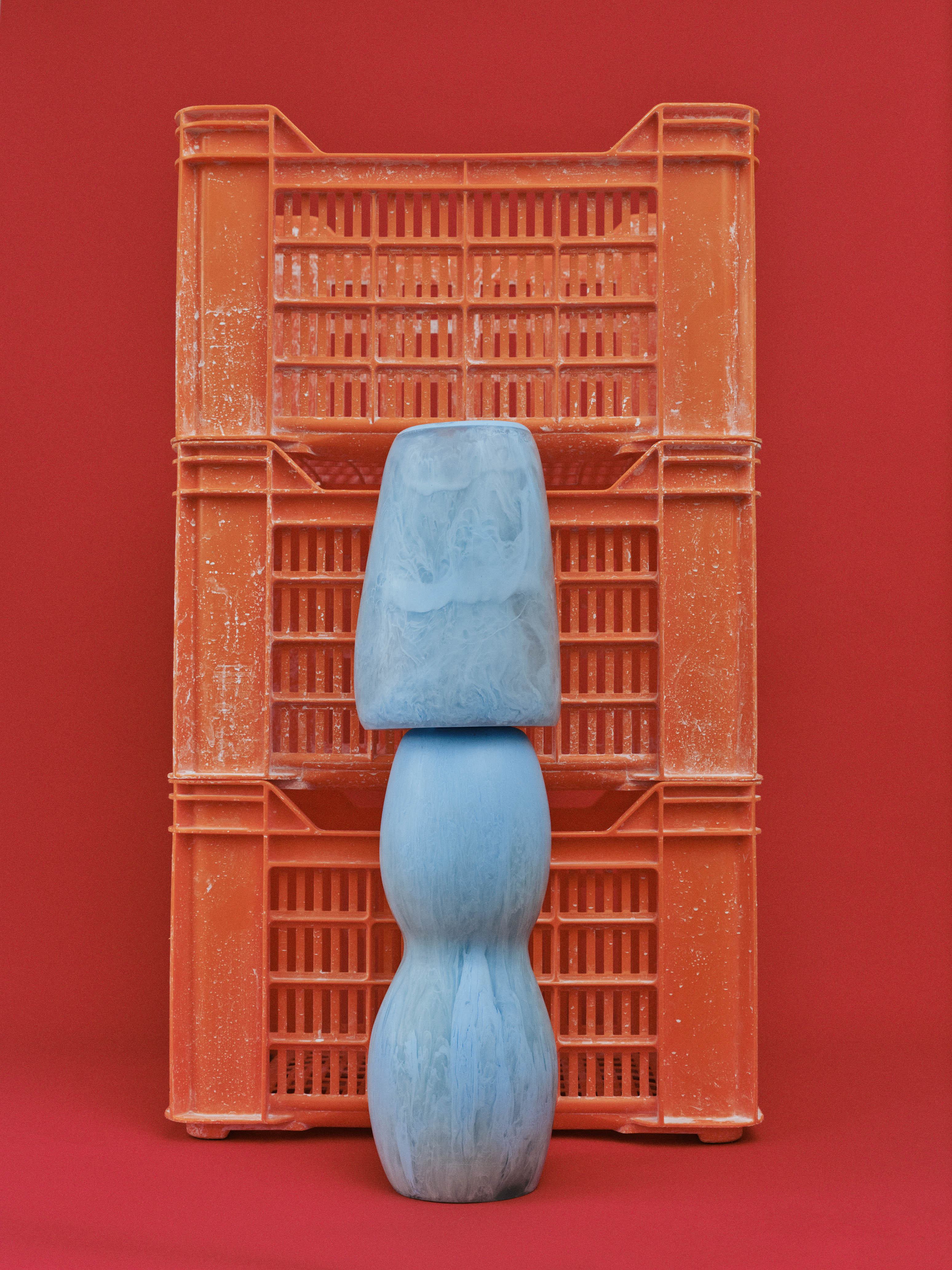 Two blue vases stacked in front of orange crates