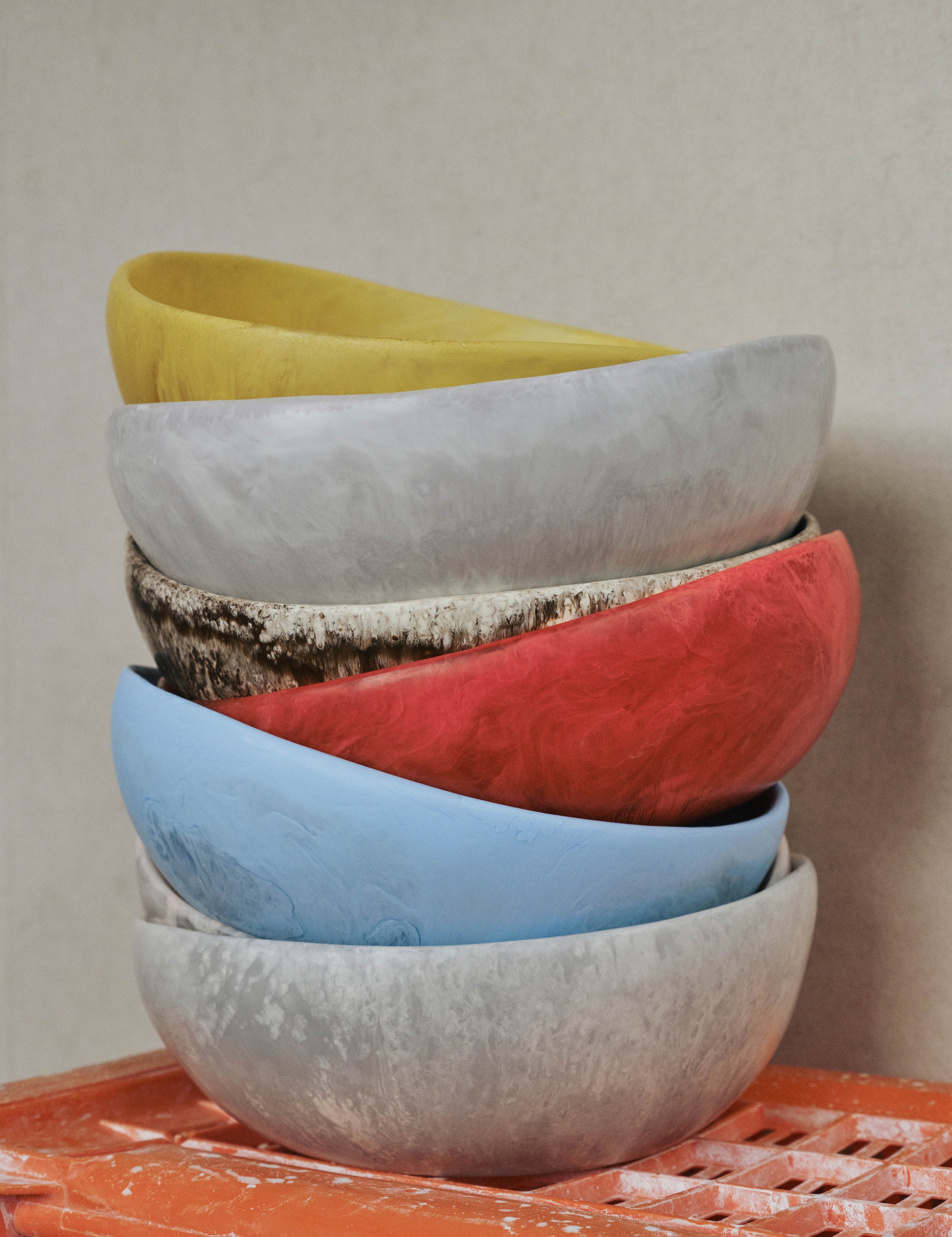 Brightly coloured salad bowls stacked on orange crate