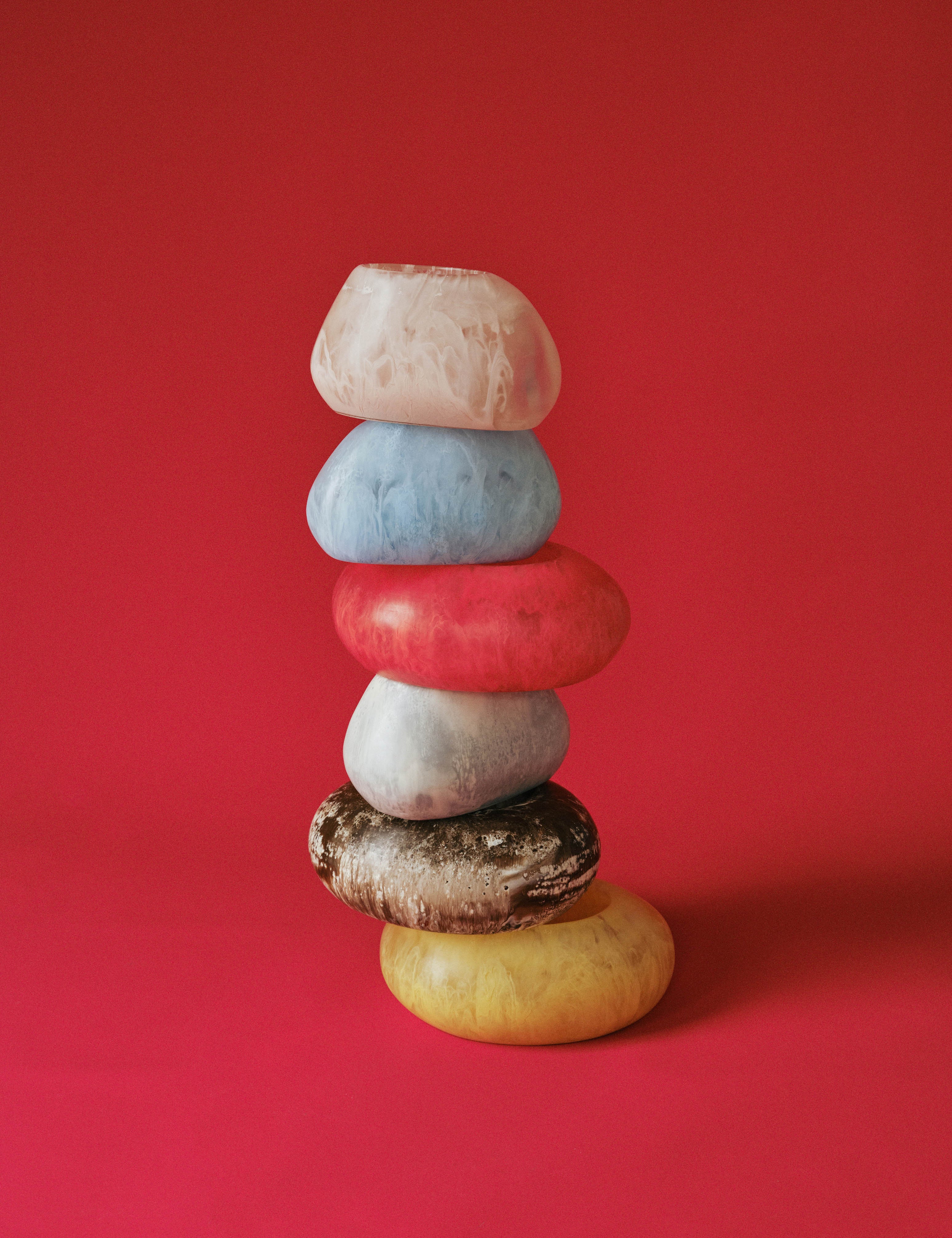 Bright coloured vases stacked on a red background
