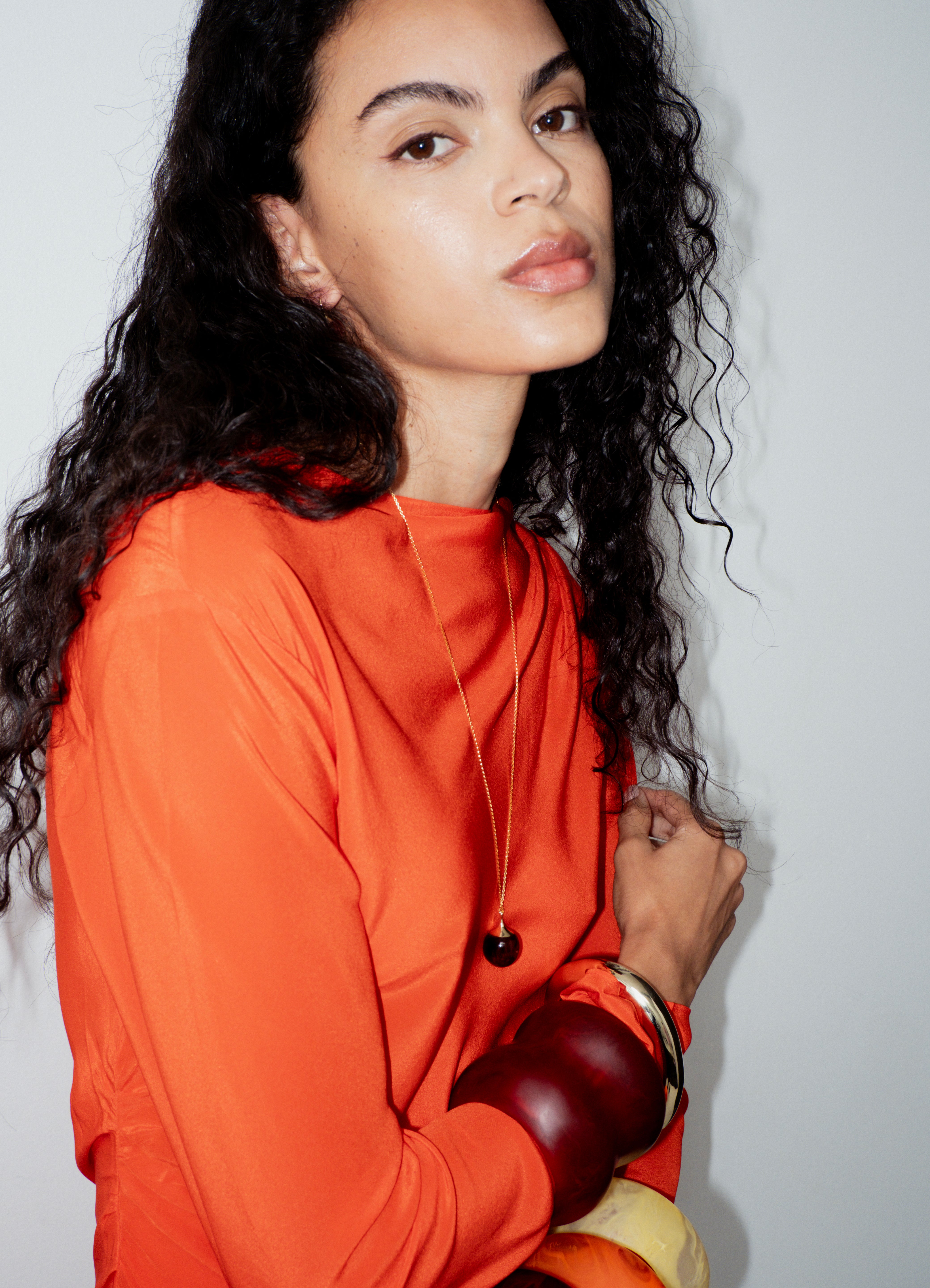 Woman wearing an orange outfit with a plain background