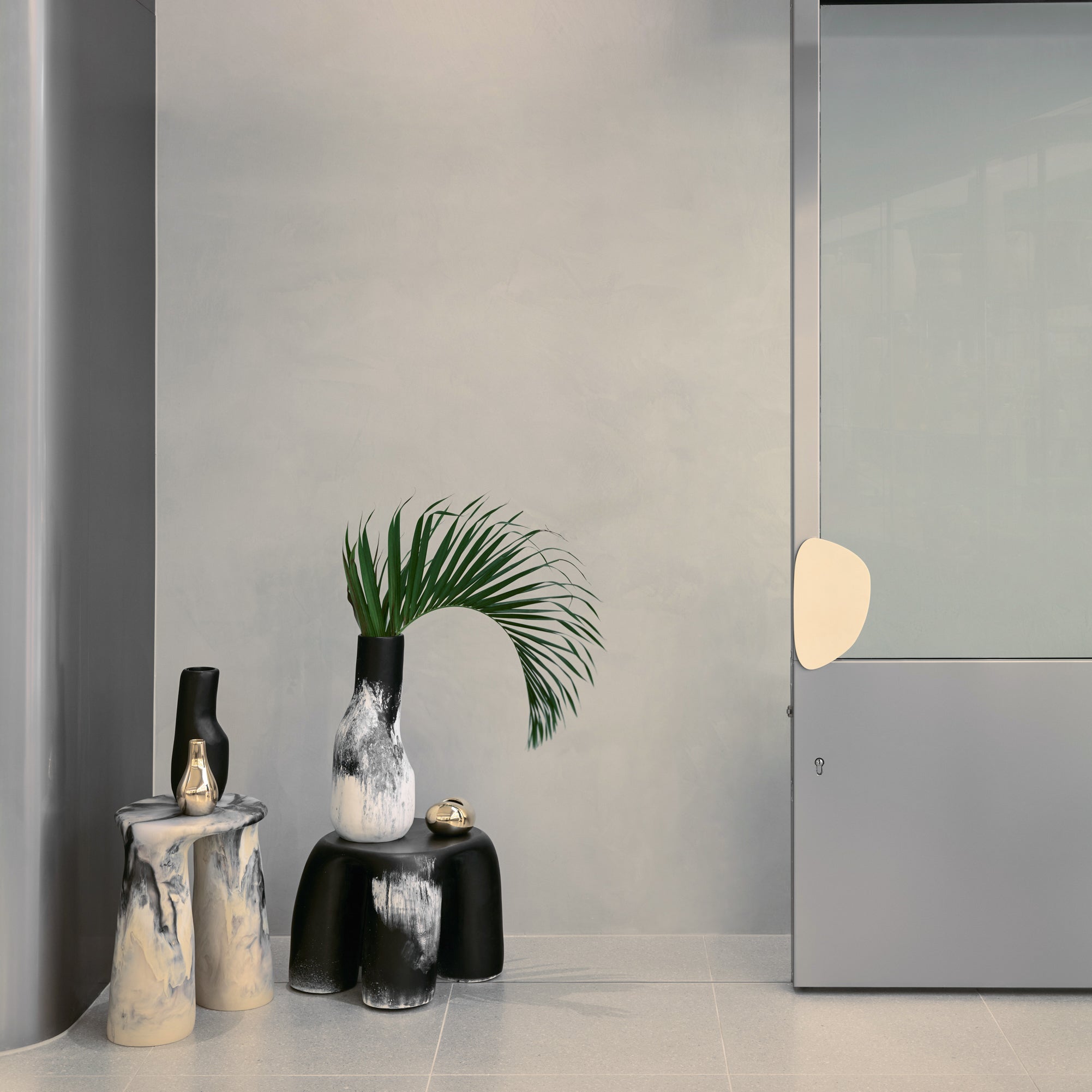 Neutral toned vases sitting on resin side tables against a plain grey wall